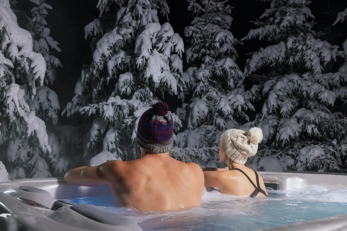 Couple enjoying the hot tub in the winter. and asking What is the ideal hot tub temperature in winter?